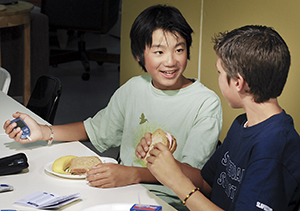 Boy at school using a glucometer during lunch.